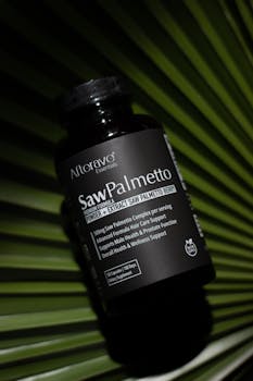 Black saw palmetto supplement bottle on a green palm leaf, enhancing health and wellness.