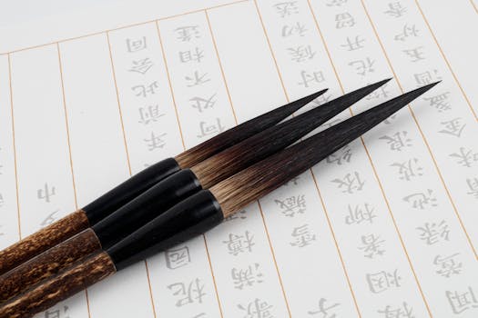 Three traditional calligraphy brushes positioned on Japanese script paper. Ideal for cultural and art themes.