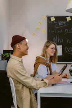 Two young professionals collaborating with technology in a modern office environment.