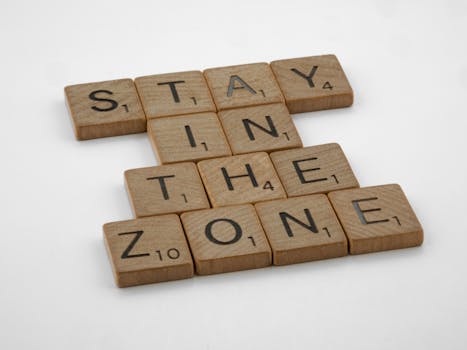 Wooden Scrabble tiles arranged to spell 'Stay in the Zone' on a white background.