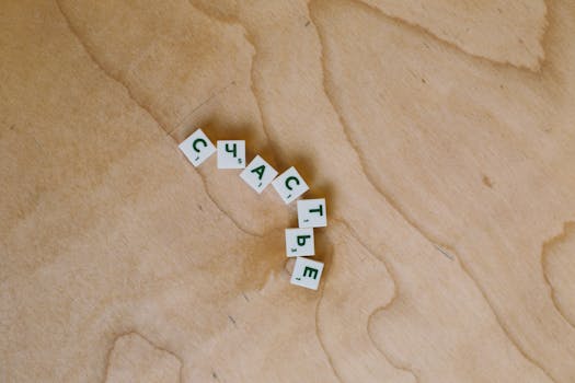 Wooden scrabble tiles spelling a Russian word on a wooden surface, creating a minimalist and conceptual image.